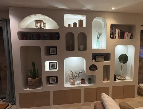 Meuble maçonné sur mesure Auriol Mur de rangement moderne avec niches éclairées, plantes et objets décoratifs.