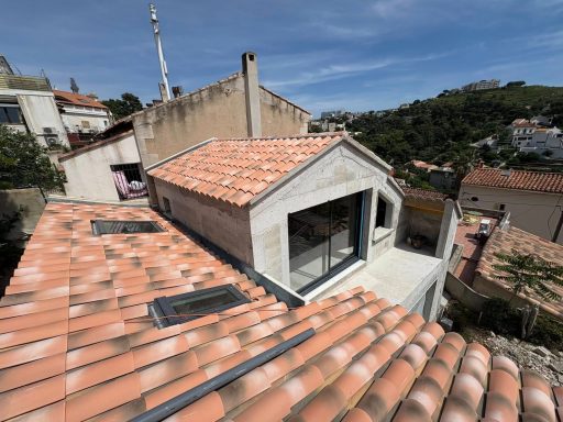 Extension par élévation Marseille Maison moderne avec toit en tuiles, vue sur des maisons environnantes.